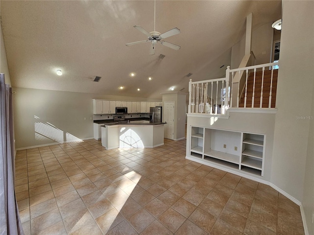 unfurnished living room with ceiling fan, built in features, a textured ceiling, vaulted ceiling, and light tile patterned floors