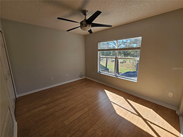 unfurnished room featuring dark hardwood / wood-style floors, ceiling fan, and a textured ceiling