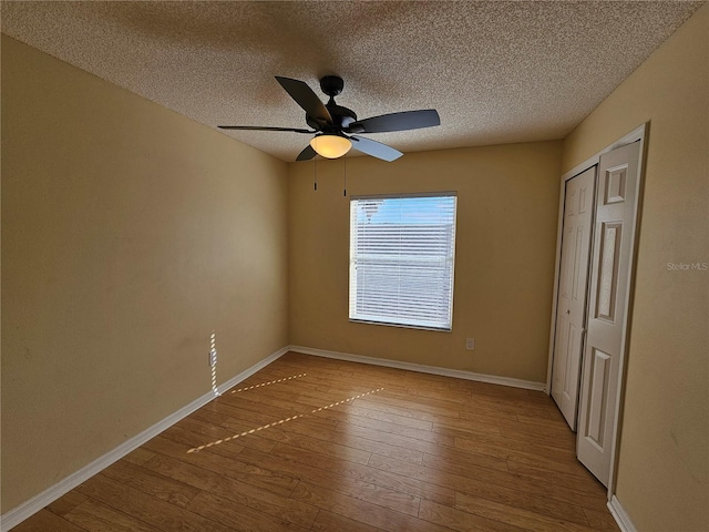 empty room featuring ceiling fan, wood-type flooring, and a textured ceiling