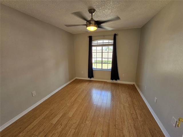 empty room with ceiling fan, light hardwood / wood-style floors, and a textured ceiling