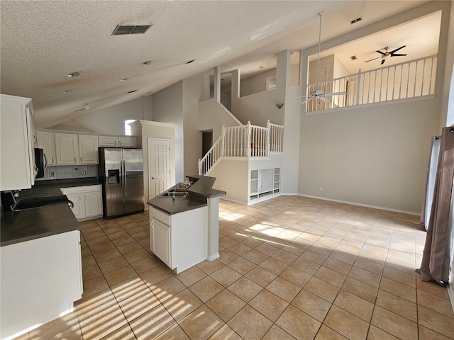 kitchen with stainless steel refrigerator with ice dispenser, white cabinetry, light tile patterned floors, kitchen peninsula, and ceiling fan