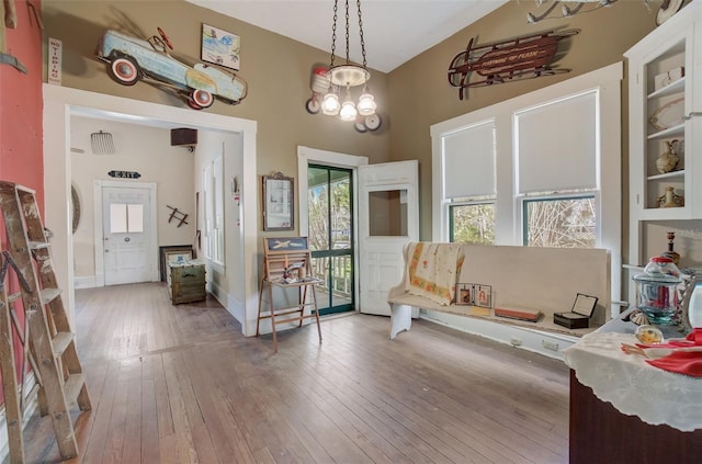 sitting room with wood-type flooring, built in shelves, a high ceiling, and an inviting chandelier