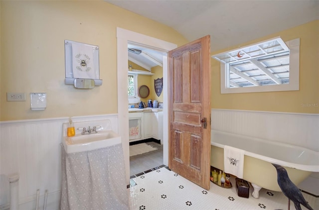 bathroom with a washtub, sink, vaulted ceiling, and hardwood / wood-style flooring