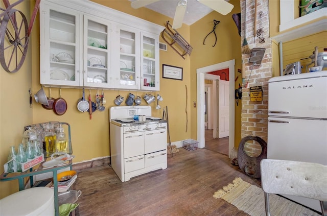 kitchen featuring ceiling fan, white range with gas cooktop, brick wall, and dark wood-type flooring