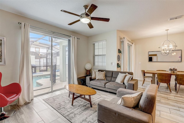 living room with ceiling fan with notable chandelier and a healthy amount of sunlight