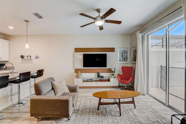 living room featuring ceiling fan and sink