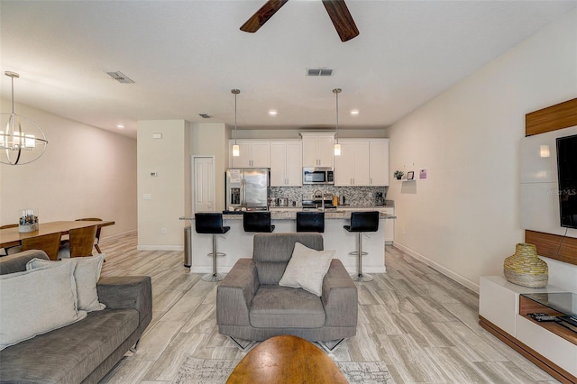 living room featuring ceiling fan with notable chandelier and light hardwood / wood-style flooring