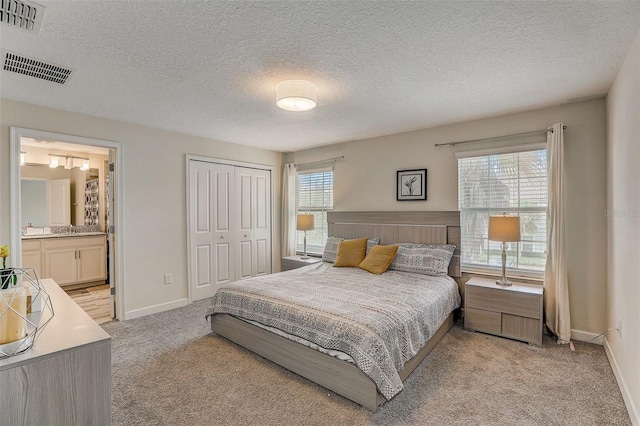 carpeted bedroom featuring connected bathroom, a closet, multiple windows, and a textured ceiling