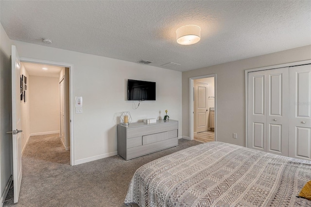 bedroom with dark carpet, a closet, a textured ceiling, and ensuite bathroom