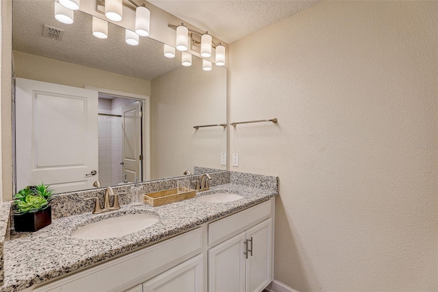 bathroom featuring a textured ceiling and dual vanity