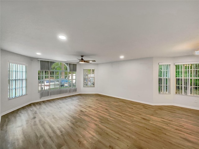 spare room with a healthy amount of sunlight, ceiling fan, and dark hardwood / wood-style flooring