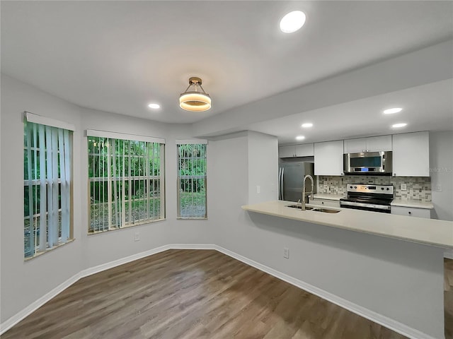 kitchen featuring stainless steel appliances, wood-type flooring, white cabinets, backsplash, and sink