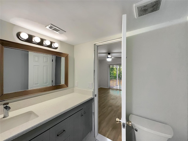 bathroom featuring toilet, wood-type flooring, ceiling fan, and vanity with extensive cabinet space