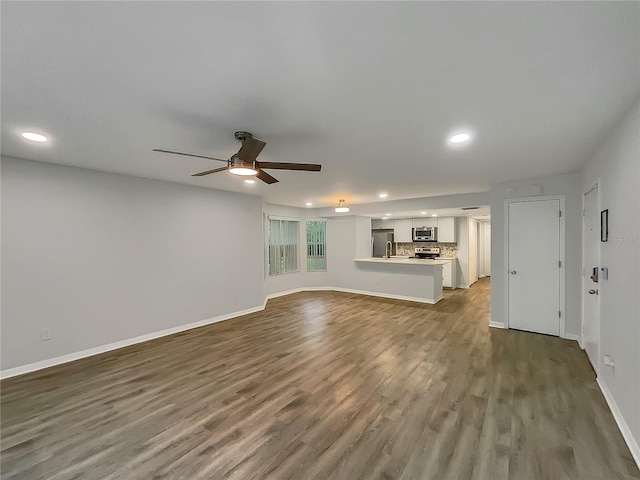 unfurnished living room featuring ceiling fan and hardwood / wood-style flooring