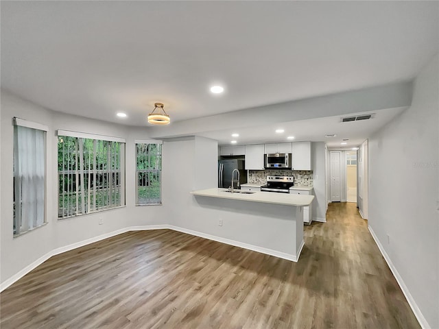 kitchen featuring stainless steel appliances, tasteful backsplash, white cabinets, light wood-type flooring, and sink