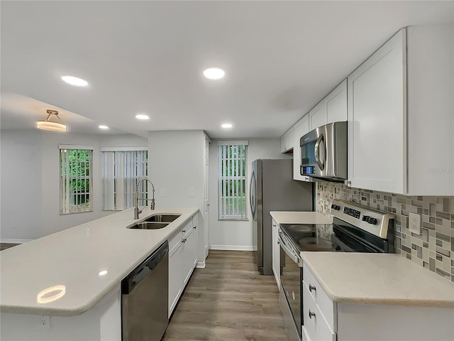 kitchen featuring plenty of natural light, light hardwood / wood-style floors, white cabinetry, appliances with stainless steel finishes, and sink