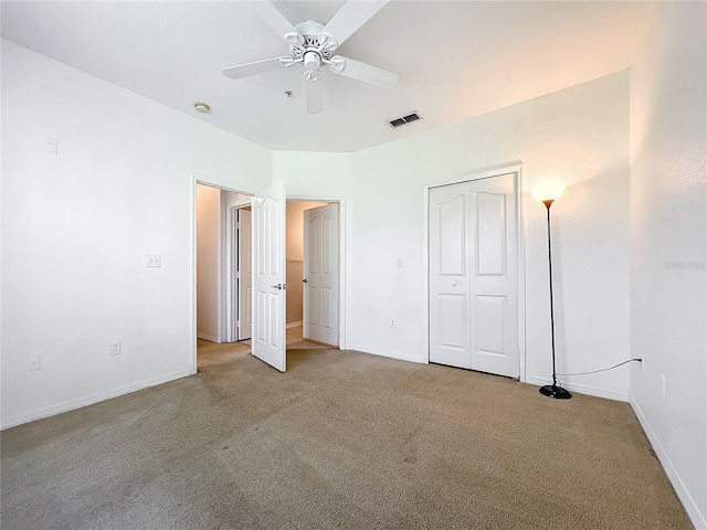 unfurnished bedroom featuring light carpet, a closet, and ceiling fan