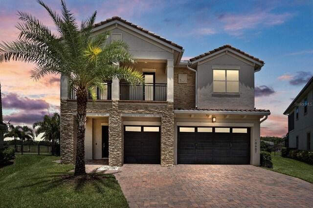 view of front of property featuring a balcony, a garage, and a lawn