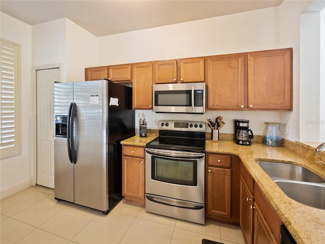 kitchen with light stone countertops, light tile patterned floors, stainless steel appliances, and sink