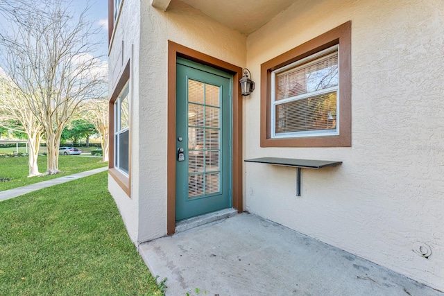 view of exterior entry featuring a lawn