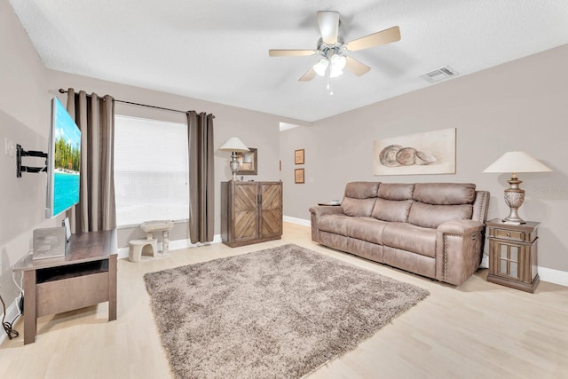 living room featuring a textured ceiling, ceiling fan, and light wood-type flooring