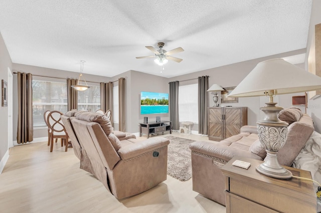 living room with a textured ceiling, ceiling fan, and light hardwood / wood-style flooring