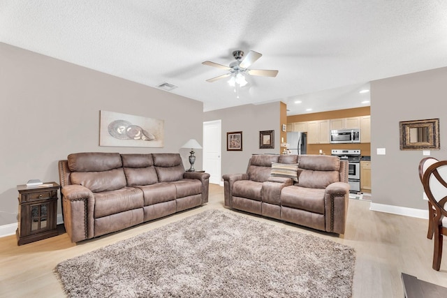 living room featuring a textured ceiling, ceiling fan, and light hardwood / wood-style flooring