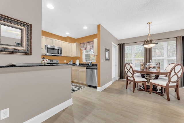 kitchen featuring pendant lighting, appliances with stainless steel finishes, a textured ceiling, and light wood-type flooring