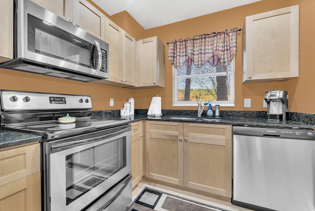 kitchen with stainless steel appliances, sink, light brown cabinetry, and dark stone counters