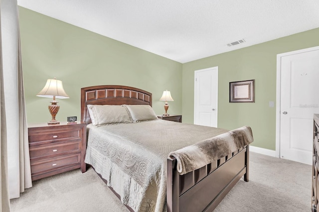 bedroom featuring light colored carpet and a textured ceiling