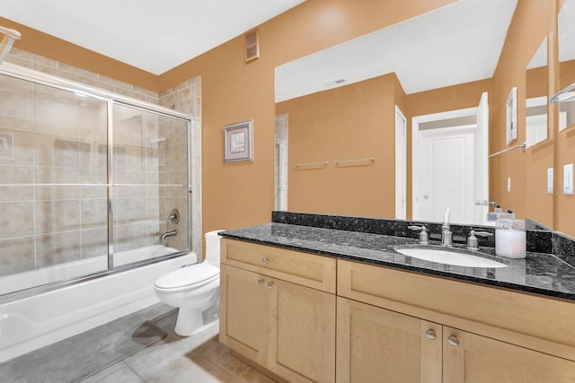 full bathroom featuring toilet, tile patterned floors, vanity, and bath / shower combo with glass door