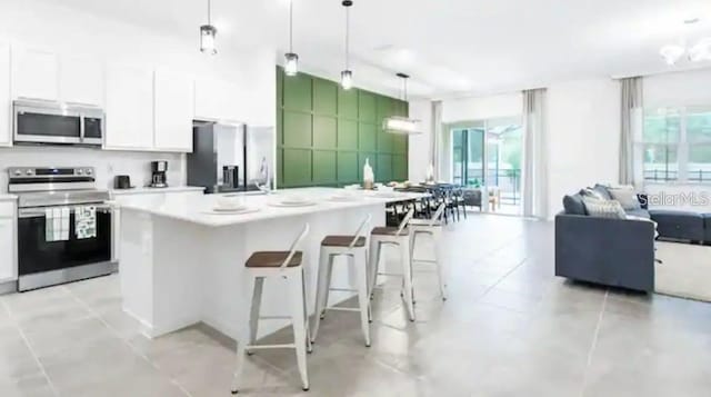 kitchen featuring white cabinetry, an inviting chandelier, a kitchen breakfast bar, stainless steel appliances, and pendant lighting