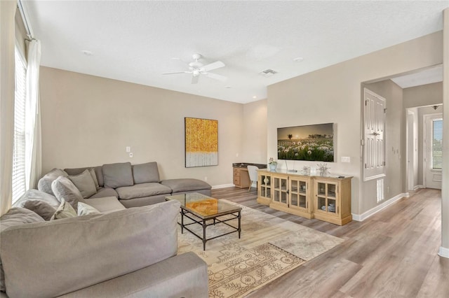 living room featuring light hardwood / wood-style floors, a textured ceiling, and ceiling fan