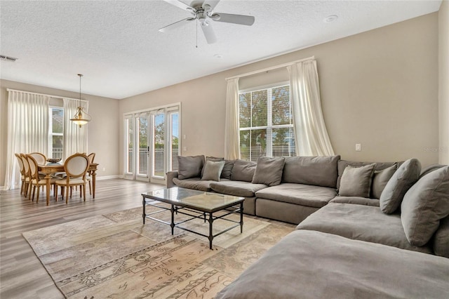 living room with light hardwood / wood-style flooring, a healthy amount of sunlight, and ceiling fan