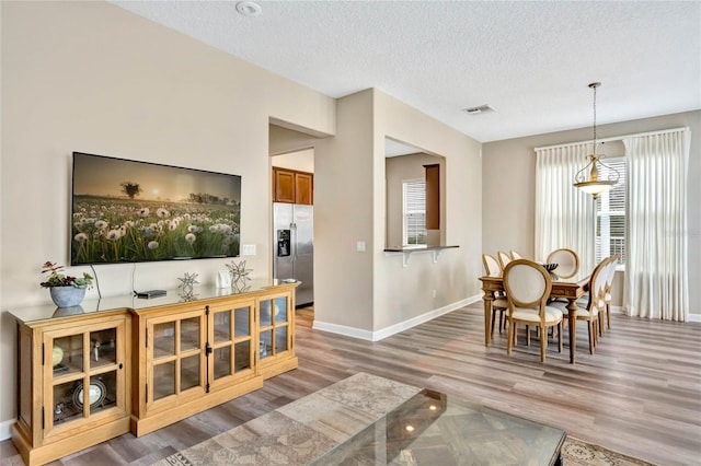 dining room featuring a textured ceiling, wood-type flooring, and a wealth of natural light