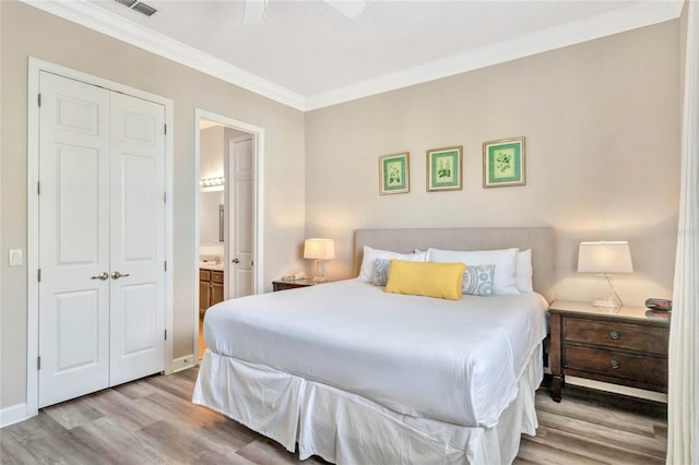 bedroom featuring connected bathroom, a closet, light hardwood / wood-style flooring, ornamental molding, and ceiling fan