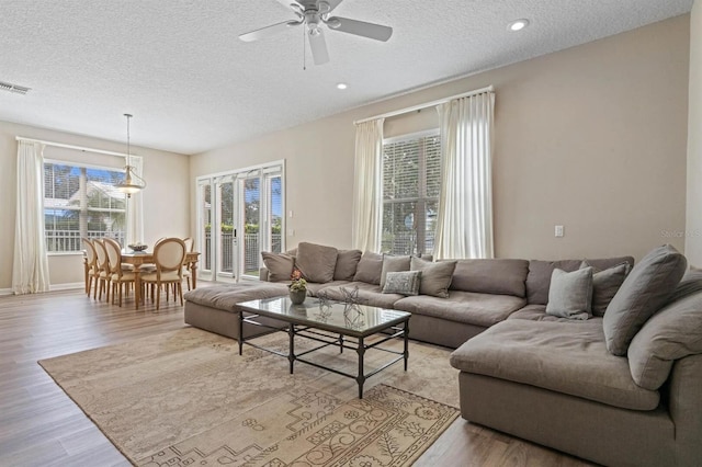 living room featuring light hardwood / wood-style floors, a textured ceiling, and ceiling fan