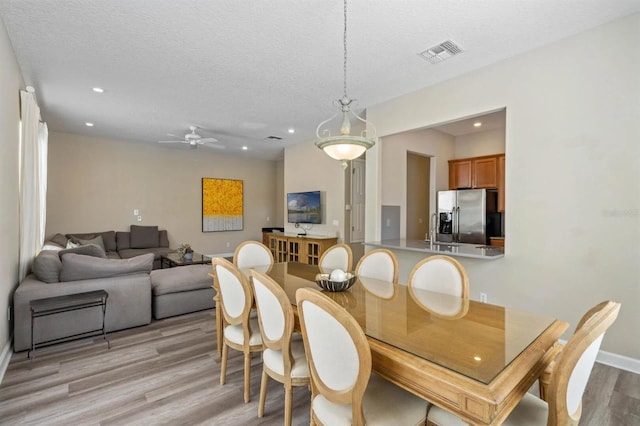 dining room with light hardwood / wood-style flooring, a textured ceiling, and ceiling fan