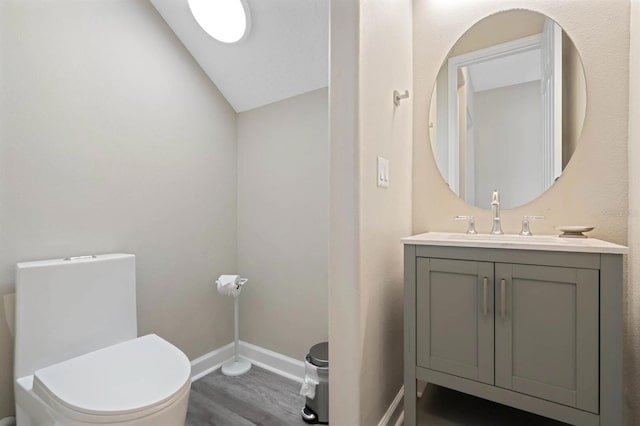 bathroom featuring vanity, hardwood / wood-style floors, vaulted ceiling, and toilet