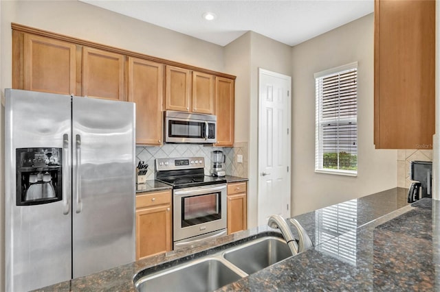 kitchen with dark stone countertops, tasteful backsplash, stainless steel appliances, and sink