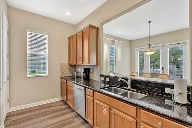 kitchen featuring sink, hanging light fixtures, stainless steel dishwasher, dark stone countertops, and hardwood / wood-style flooring