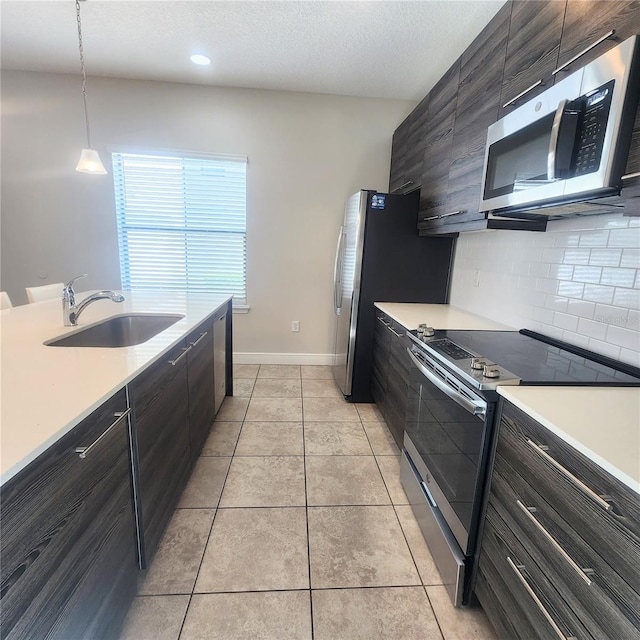 kitchen with sink, stainless steel appliances, light tile floors, tasteful backsplash, and pendant lighting