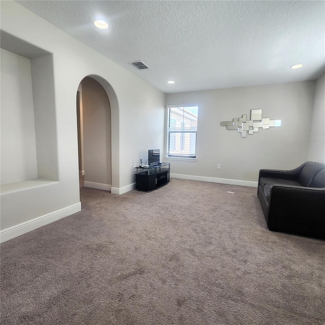 sitting room with a textured ceiling and dark carpet