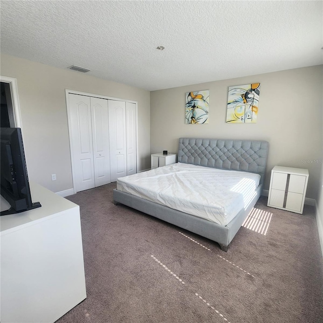 bedroom with a textured ceiling, carpet flooring, and a closet