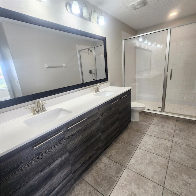 bathroom with toilet, a shower with door, double vanity, a textured ceiling, and tile flooring