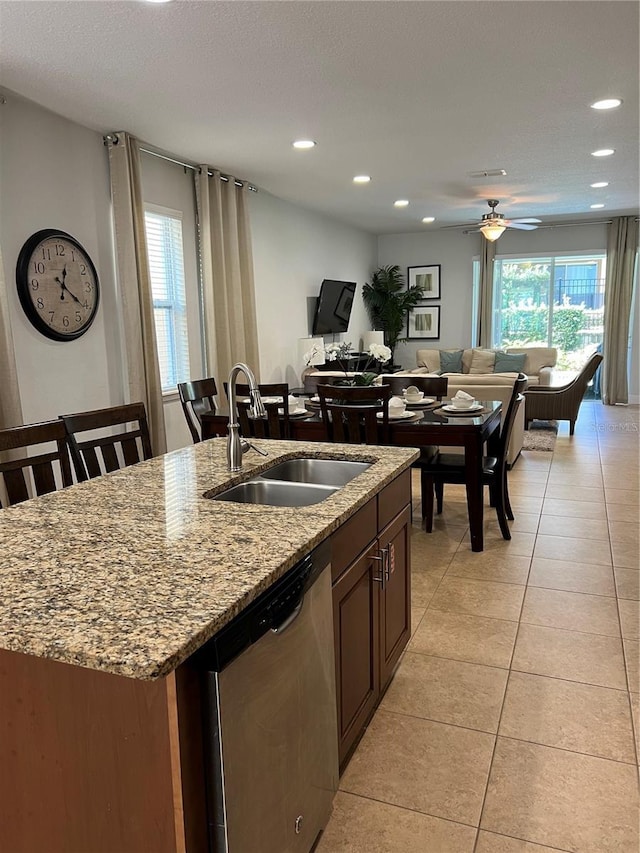 kitchen with stainless steel dishwasher, a kitchen island with sink, open floor plan, and a sink