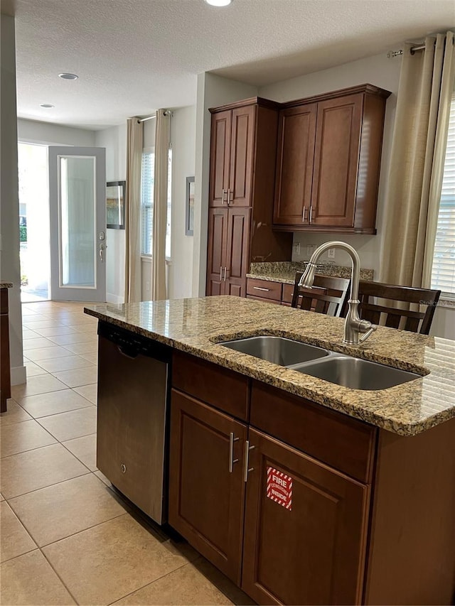 kitchen featuring light stone counters, dishwasher, a sink, and light tile patterned floors