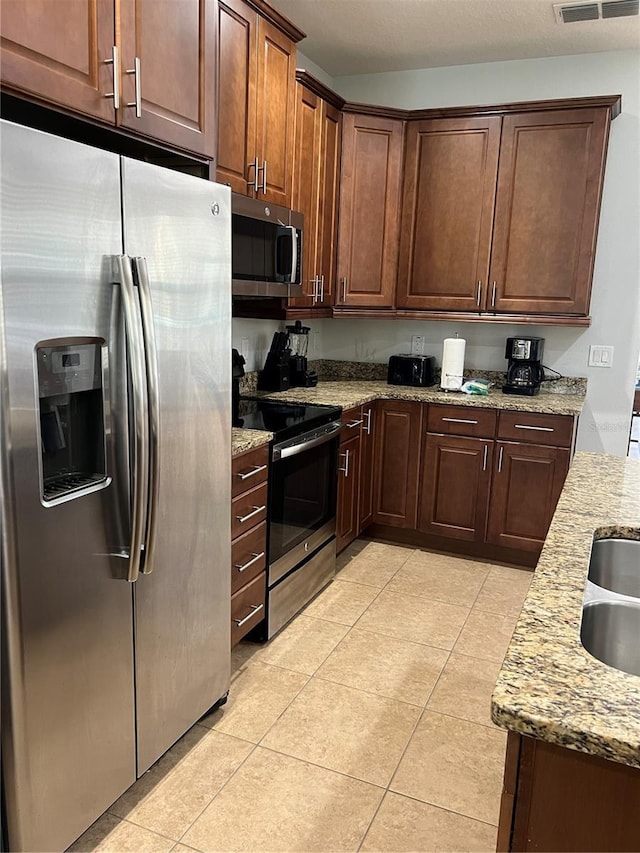 kitchen featuring light stone countertops, visible vents, stainless steel appliances, and light tile patterned flooring