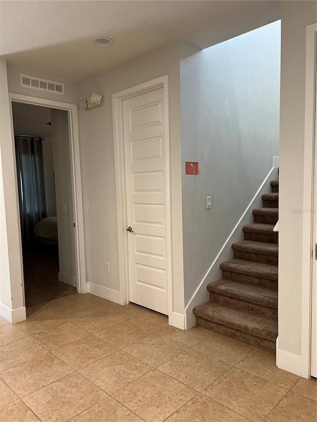 staircase with tile patterned flooring, visible vents, and baseboards