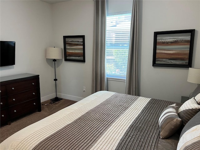 bedroom with dark colored carpet and baseboards